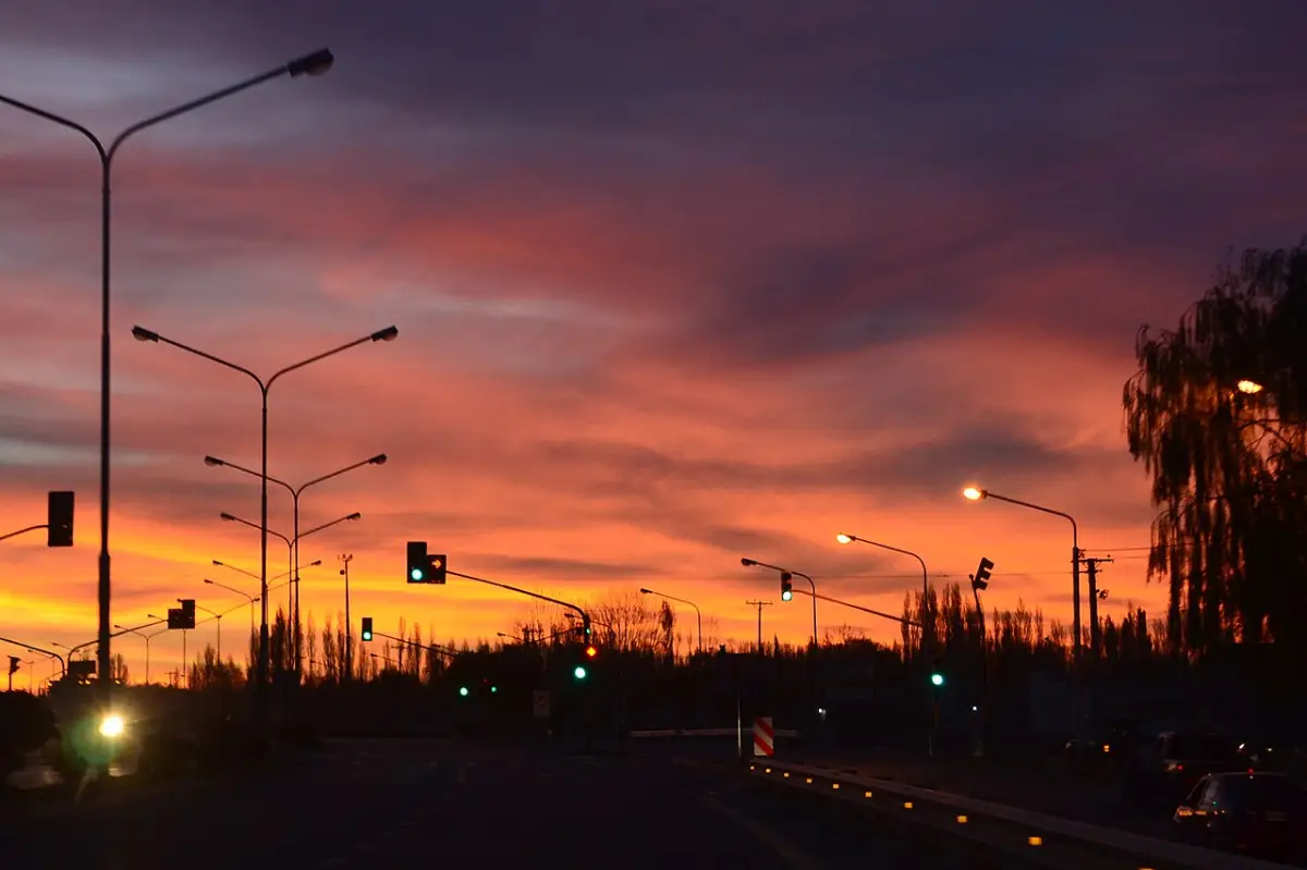 Atardecer sobre una avenida de Neuquén con las farolas encendidas